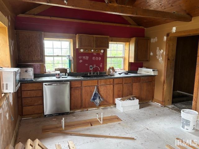 kitchen featuring a sink, vaulted ceiling with beams, stainless steel dishwasher, and brown cabinetry