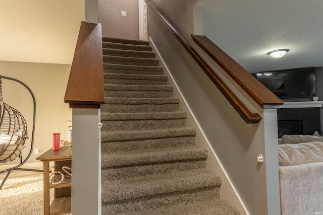 stairs with a fireplace and carpet flooring