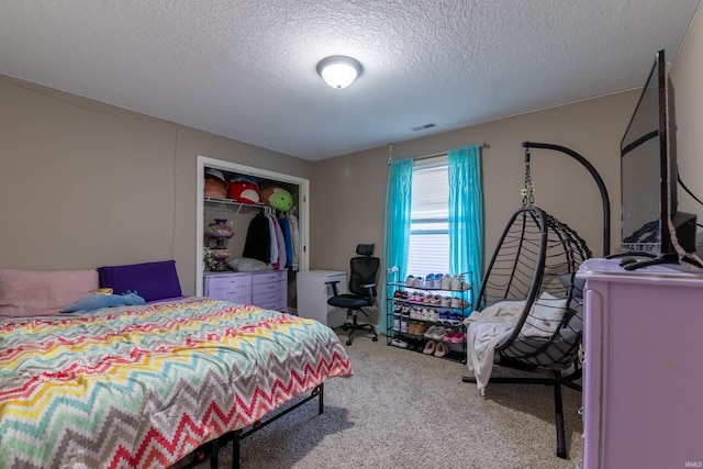 carpeted bedroom featuring visible vents, a textured ceiling, and a closet