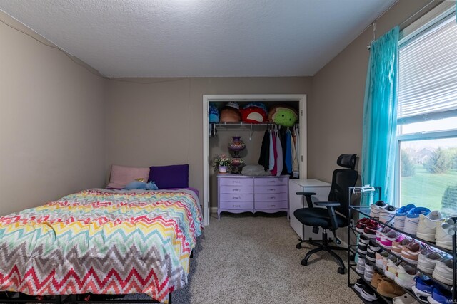 carpeted bedroom with a textured ceiling and a closet