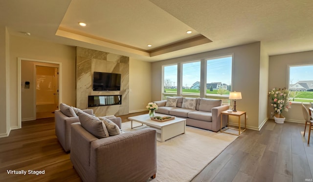 17665 Lakota Ct, Huntertown, IN 46748 - living room featuring light wood finished floors, baseboards, a tray ceiling, recessed lighting, and a fireplace