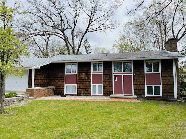 view of front of house featuring a garage, roof with shingles, a front yard, and a chimney
