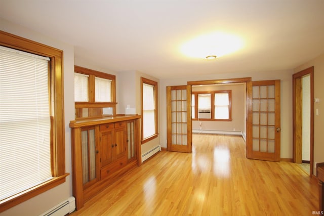 unfurnished room featuring french doors, a baseboard heating unit, baseboard heating, and light wood-type flooring