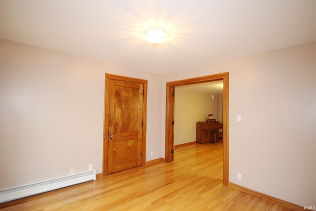 spare room with light wood-type flooring, baseboards, and baseboard heating