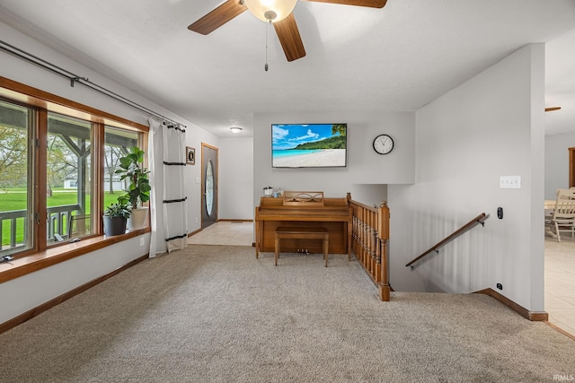 living room with baseboards, a ceiling fan, and light carpet