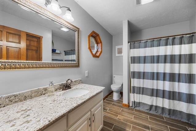 full bathroom with vanity, toilet, a textured ceiling, a shower with shower curtain, and wood tiled floor