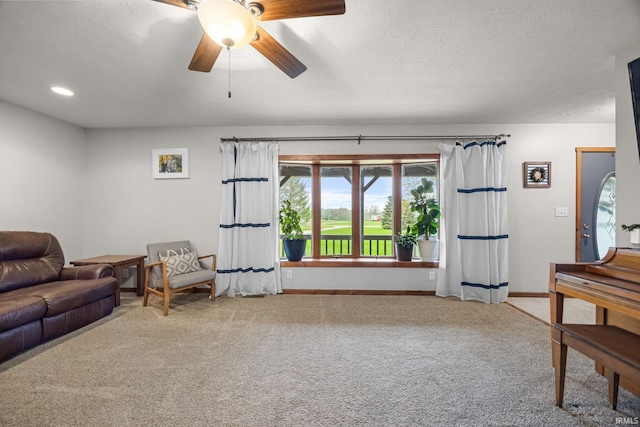 carpeted living room with a ceiling fan, baseboards, and a textured ceiling