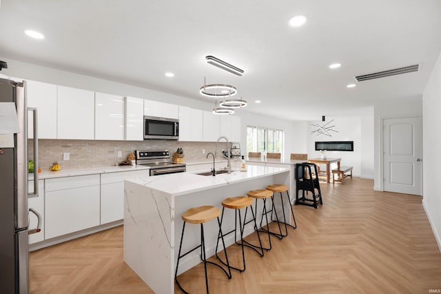 13440 N Summerhill Dr, Albany, IN 47320 - kitchen with visible vents, a kitchen bar, white cabinets, a sink, and stainless steel appliances
