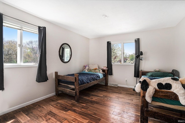 bedroom with baseboards, visible vents, and dark wood-type flooring
