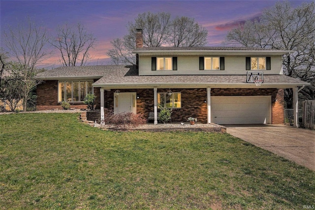 split level home featuring an attached garage, a front lawn, brick siding, a chimney, and concrete driveway