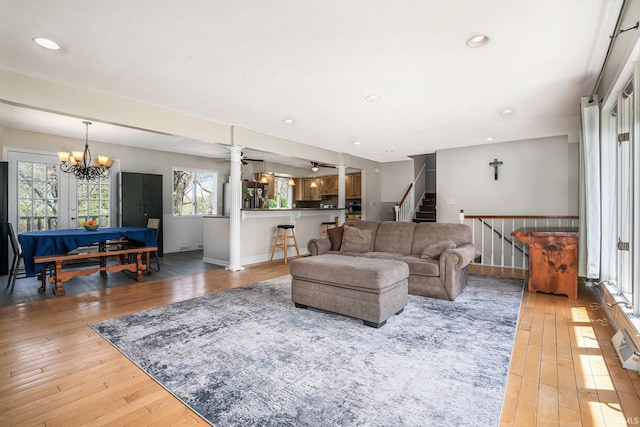 living room with baseboards, stairway, light wood-type flooring, recessed lighting, and ceiling fan with notable chandelier