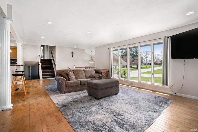 living room with ornate columns, recessed lighting, hardwood / wood-style flooring, and stairway