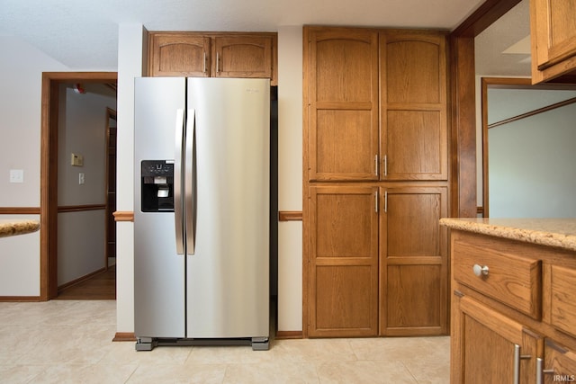kitchen featuring brown cabinets, baseboards, and stainless steel fridge with ice dispenser