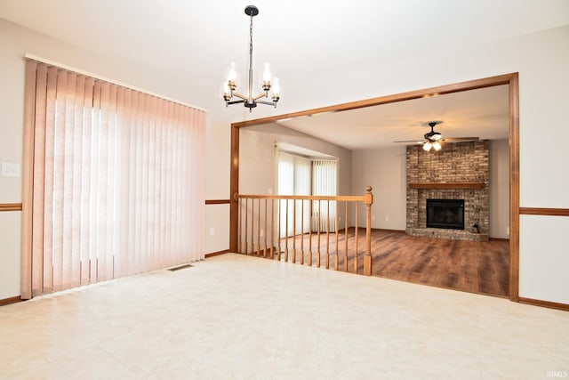 unfurnished living room with a brick fireplace, baseboards, visible vents, and ceiling fan with notable chandelier