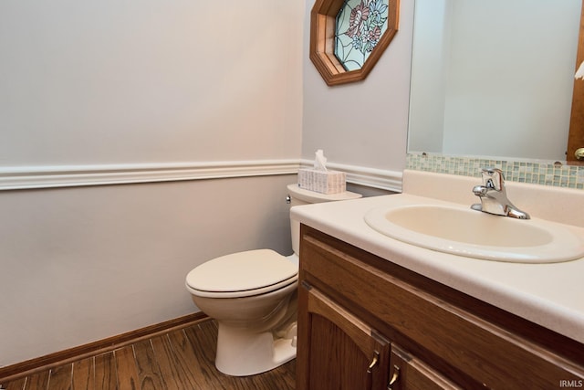 half bath featuring vanity, wood finished floors, and toilet