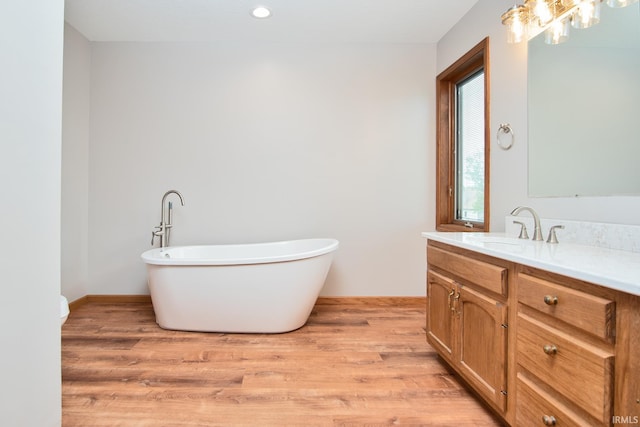 bathroom featuring vanity, a soaking tub, recessed lighting, and wood finished floors