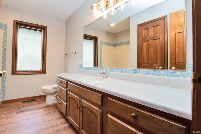 bathroom with vanity, toilet, baseboards, wood finished floors, and visible vents