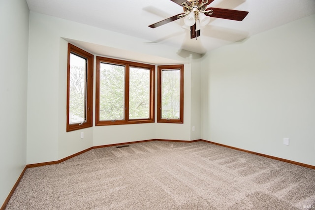 spare room with baseboards, carpet, a ceiling fan, and visible vents