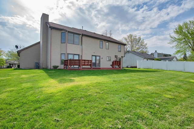 back of property with a lawn, fence, a chimney, and a deck