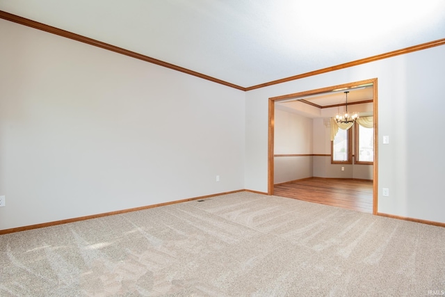 empty room with baseboards, an inviting chandelier, ornamental molding, and carpet
