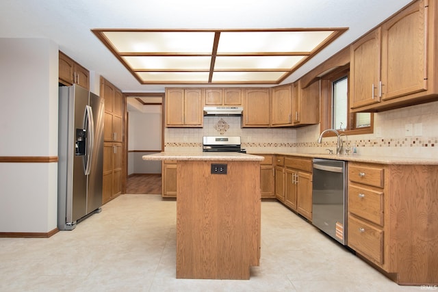 kitchen with a center island, a sink, light countertops, under cabinet range hood, and stainless steel appliances