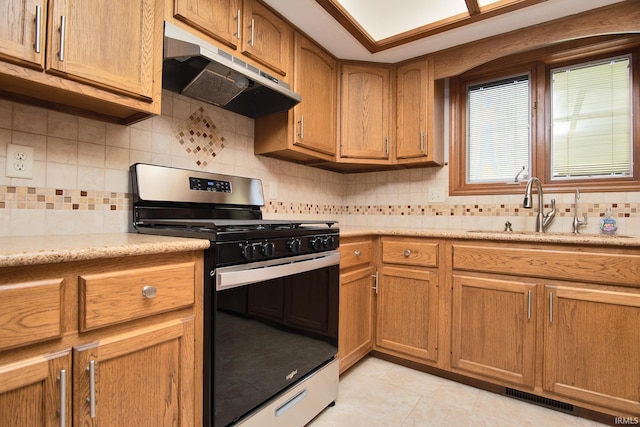kitchen featuring backsplash, visible vents, stainless steel range with gas stovetop, a sink, and under cabinet range hood