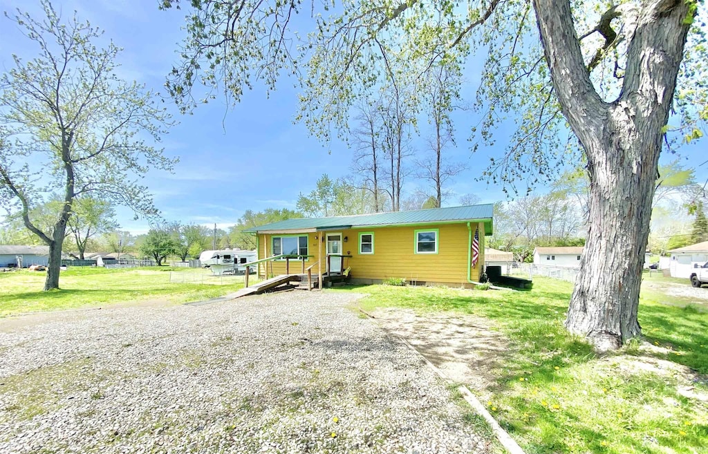 view of front of home with metal roof and a front lawn