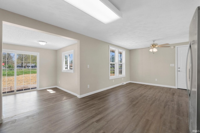 unfurnished living room featuring baseboards, a ceiling fan, and dark wood-style flooring
