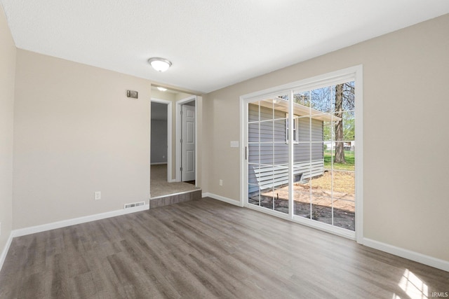 empty room with baseboards, wood finished floors, and visible vents