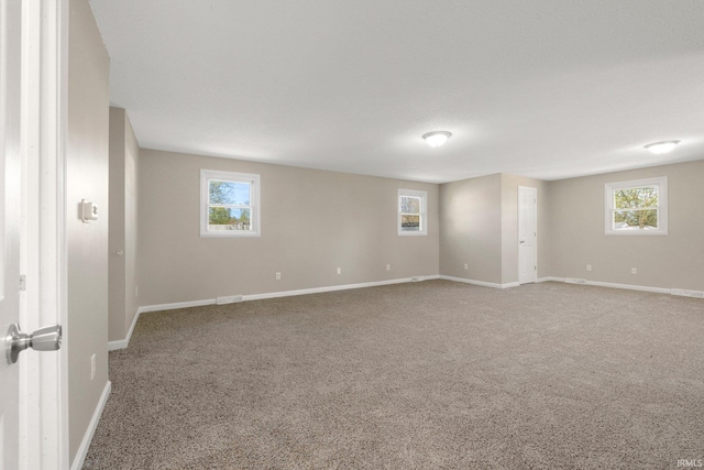 carpeted spare room featuring baseboards and a healthy amount of sunlight