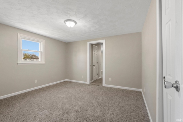spare room with baseboards, a textured ceiling, and carpet floors