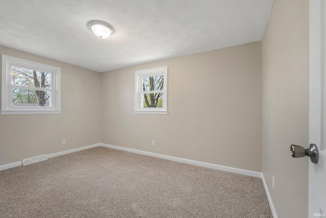 spare room with baseboards, carpet, and visible vents