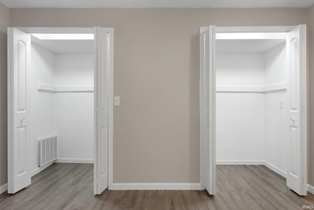unfurnished bedroom with baseboards, a closet, wood finished floors, and visible vents