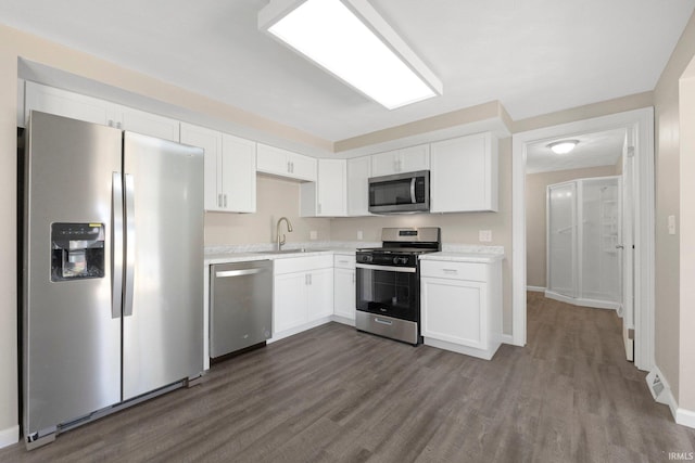 kitchen with dark wood-type flooring, light countertops, white cabinetry, a sink, and appliances with stainless steel finishes
