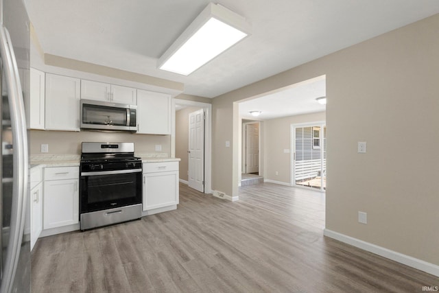 kitchen with baseboards, light wood-type flooring, light countertops, white cabinets, and stainless steel appliances