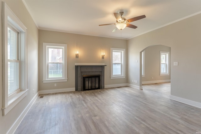 unfurnished living room featuring arched walkways, plenty of natural light, and ceiling fan