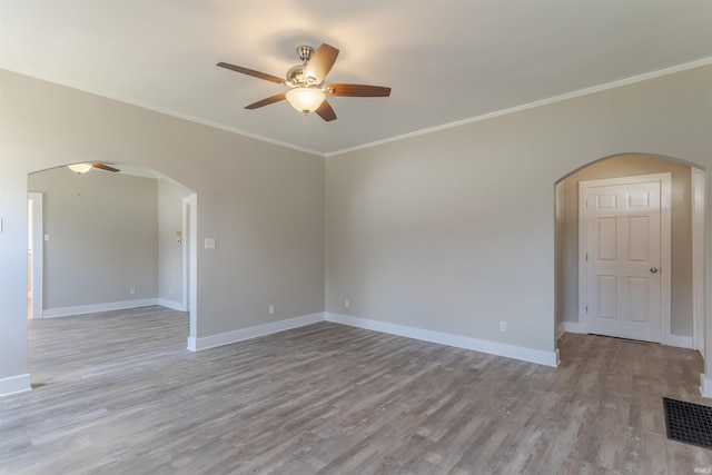 unfurnished room featuring arched walkways, light wood-style flooring, and ceiling fan