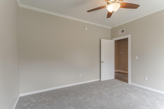 carpeted empty room featuring visible vents, a ceiling fan, baseboards, and crown molding