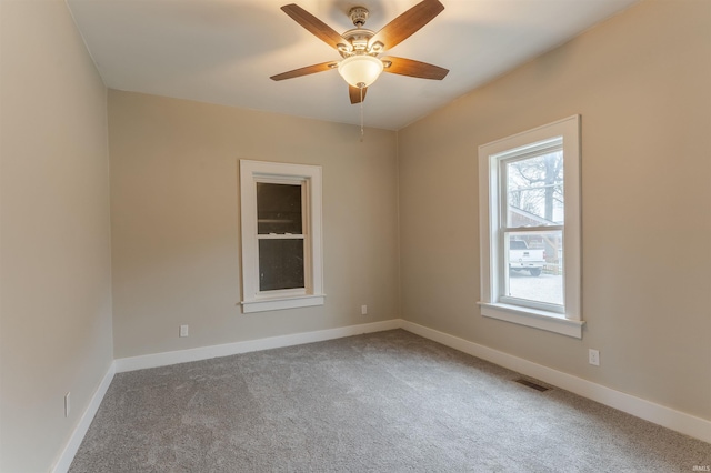 carpeted spare room with a ceiling fan, baseboards, and visible vents