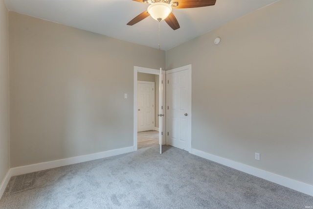 empty room with baseboards, ceiling fan, and light carpet