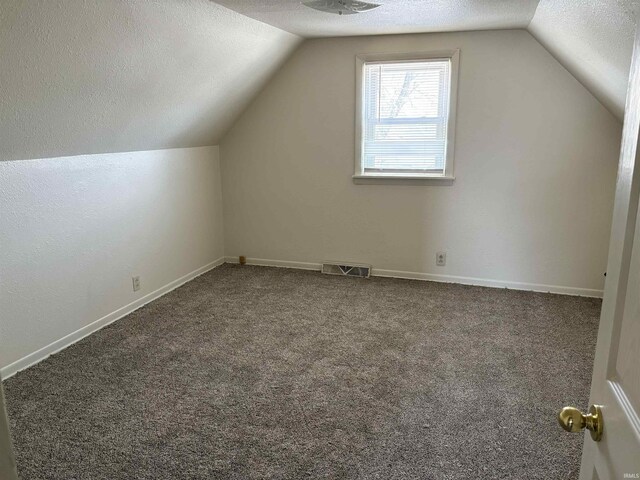 bonus room with lofted ceiling, carpet flooring, a textured ceiling, and visible vents