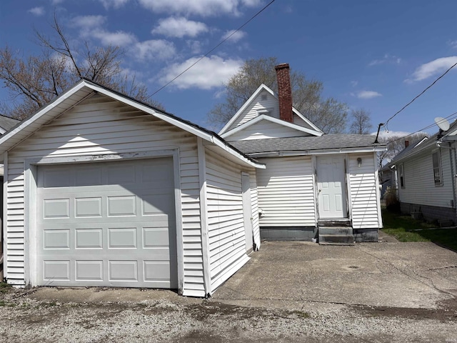 view of front of home with a chimney, a detached garage, an outdoor structure, a shingled roof, and entry steps