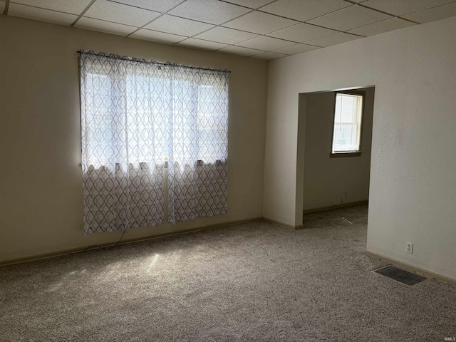 unfurnished room featuring visible vents, a paneled ceiling, carpet floors, and baseboards