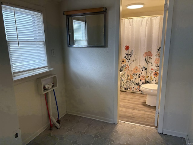 clothes washing area featuring baseboards, washer hookup, and plenty of natural light