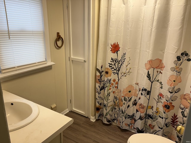 full bathroom with a shower with shower curtain, baseboards, a sink, and wood finished floors