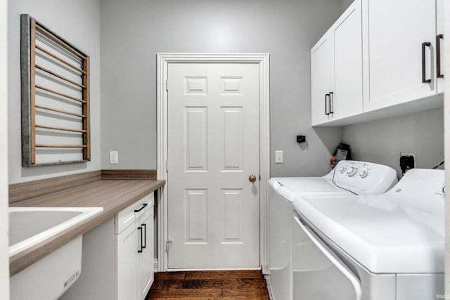 clothes washing area featuring a sink, cabinet space, dark wood finished floors, and washing machine and clothes dryer