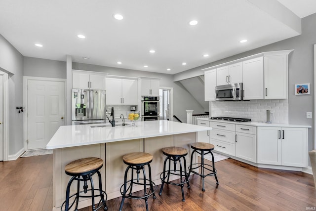 kitchen featuring backsplash, appliances with stainless steel finishes, a sink, and dark wood-type flooring