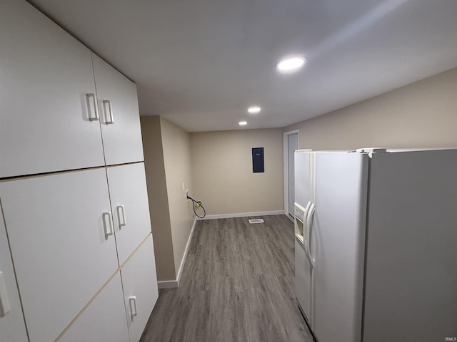 interior space featuring electric panel, wood finished floors, baseboards, white fridge with ice dispenser, and recessed lighting