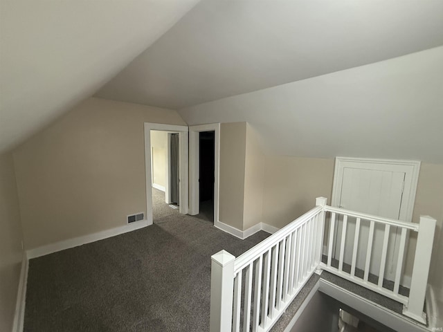 bonus room featuring baseboards, lofted ceiling, dark carpet, and visible vents