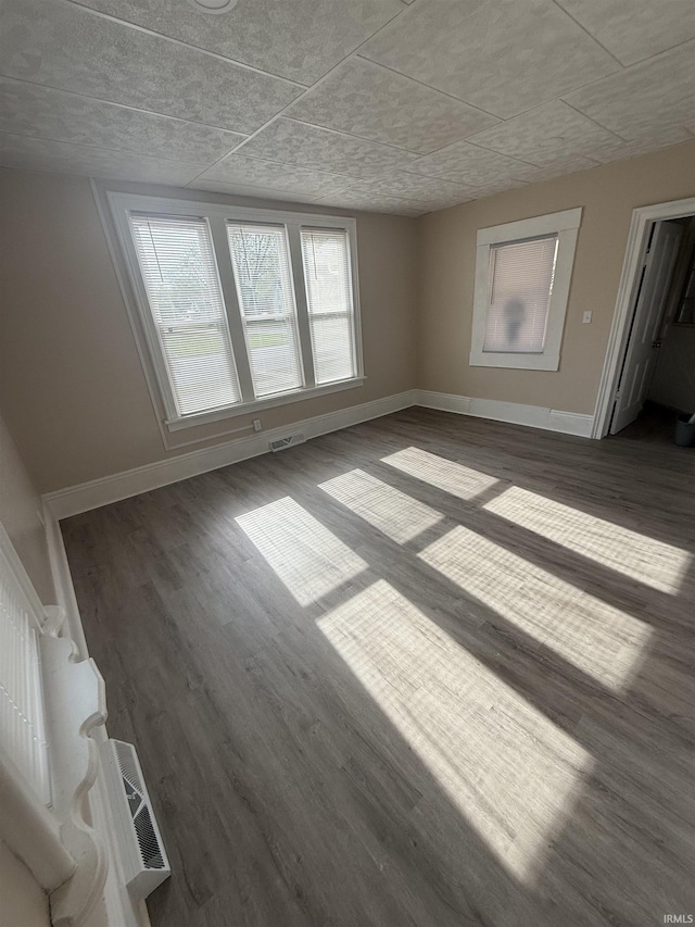 unfurnished living room featuring baseboards, dark wood-style flooring, and visible vents